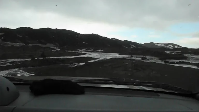 Blick durch die Windschutzscheibe auf Schneefelder und Lava Blick durch die Windschutzscheibe auf Schneefelder und Lava